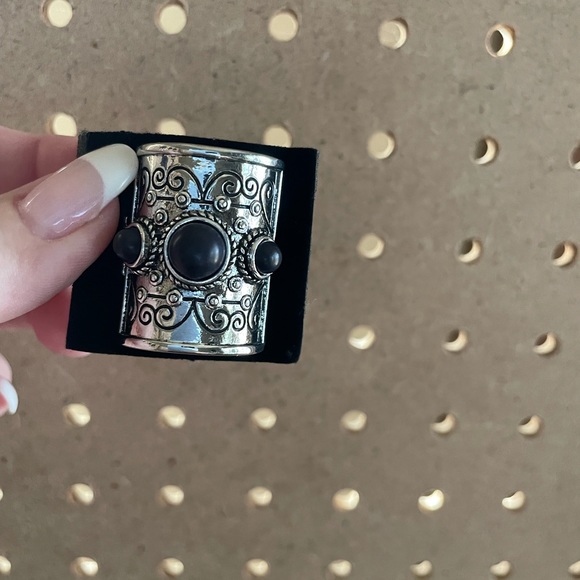 Large half shield silver ring with black matte stone accent.